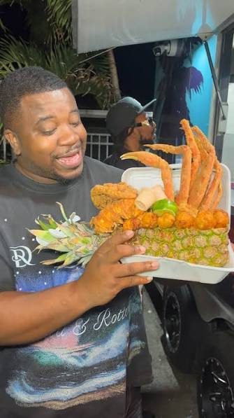 Matthew, founder of 305 Tables, holding a loaded seafood platter at a Miami food spot